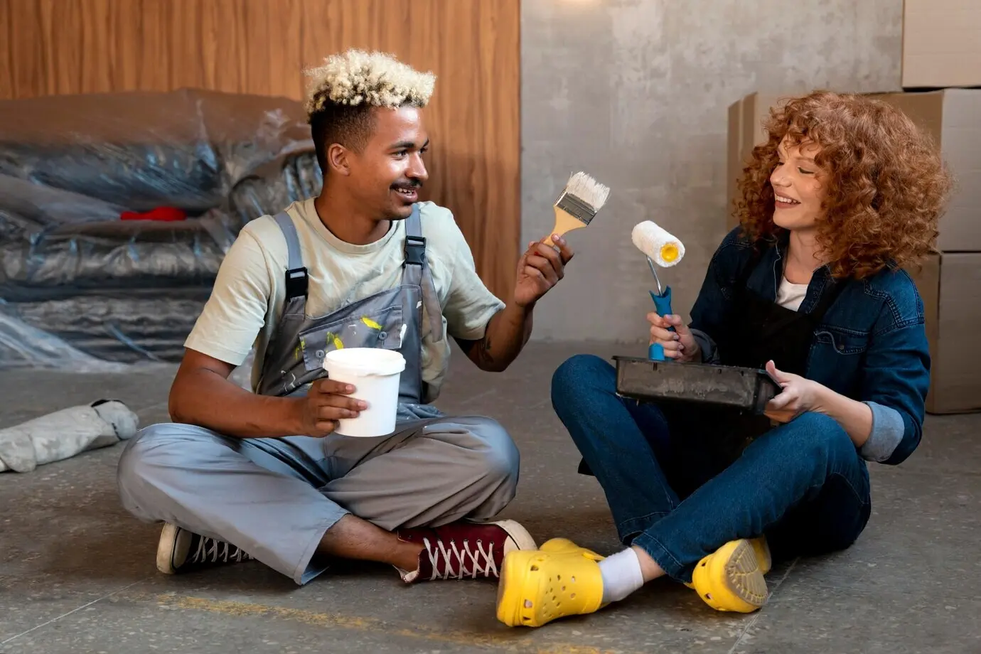 Ein Paar posiert gemeinsam in seinem neuen Zuhause, während es einen Pinsel hält.
